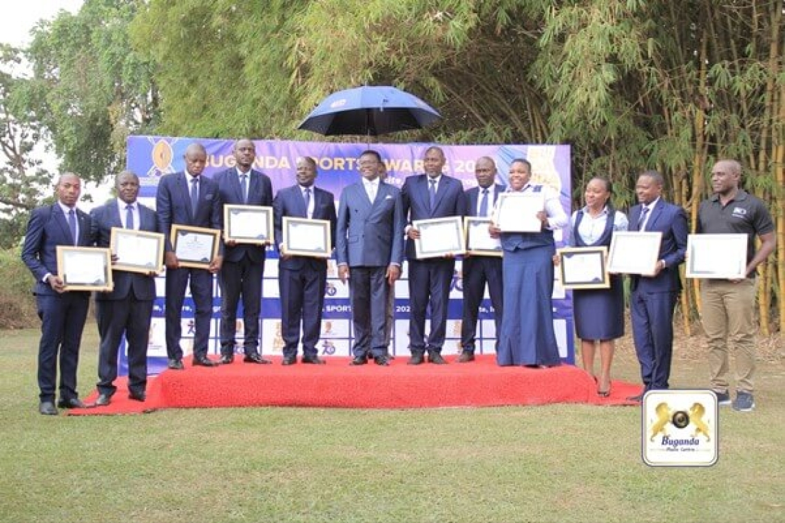 The Katikkiro (right) poses with the awarded sportsmen in a joint photo